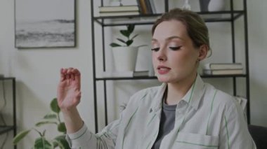 Alfabe harflerini ve sesleri ekranın dışındaki sağır öğrencilere göstererek ve ifade ederek ders sırasında ofiste oturan beyaz kadın işaret dili öğretmeninin orta ölçekli yakın çekimi.