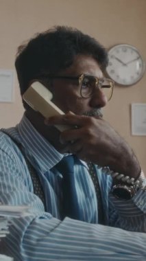 Çalışkan, olgun ofis çalışanlarının telefon görüşmelerine resmi olarak cevap veren ve 90 'larda eski bilgisayarda çalışan dikey yan görüntüleri.