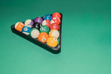 Yeşil arka planda raftaki bilardo toplarının çeşitliliği veya modern kulüp veya barda oyun oynamak için hazırlanmış bilardo masası