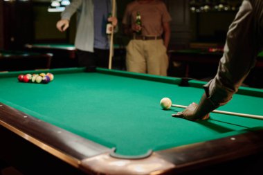 Tanımlanamayan bir adamın elinde bilardo masası, yeşil bluz ve boş vakitlerinde arkadaşlarının önünde bira içip sohbet etmesi.