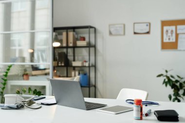 Modern pratisyen hekimin ya da diğer tıbbi malzemelerle birlikte masanın ortasında duran bilgisayarlı sanal sağlık asistanının işyeri