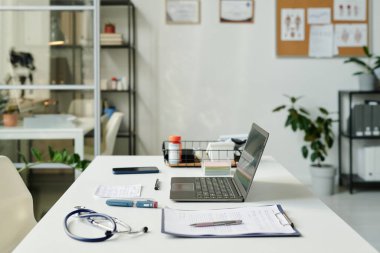 Bilgisayarlı modern klinisyen ya da sanal sağlık asistanının çalışma yeri tıbbi malzemelerle masanın ortasında duruyor.