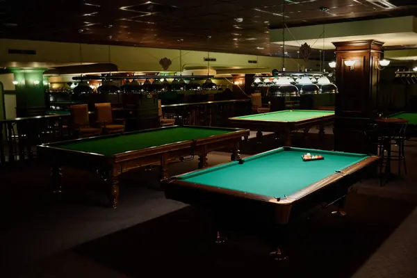 stock image Several rows of tables for playing billiards with green tops standing in spacious hall of pub or club ready for leisure games