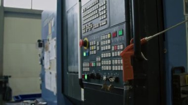 Düğmeleri ve ekranı olan büyük endüstriyel kontrol panelinin yan yatay çekimleri yok. Üretim tesisinde hava üfleme silahı asılı duruyor.