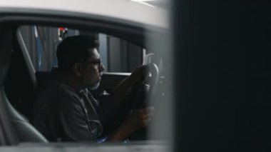 Orta yaşlı Hintli erkek tamircinin sürücü koltuğunda oturan, direksiyonu kontrol eden, sonra tablet bilgisayarda rapor formu doldurduğu orta yaşlı fotoğraf.