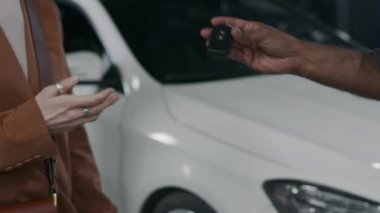 Otoparkta yapılan kontrol ve bakım çalışmalarından sonra, koyu tenli, güzel bayan müşterilere araba anahtarlarını teslim eden yavaş çekimde.