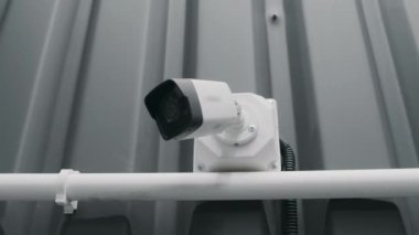 Gri duvara monte edilmiş, garajda ya da atölyede rutin çekim yapan, beyaz dijital kamera görüntüsü alan kimse yok.