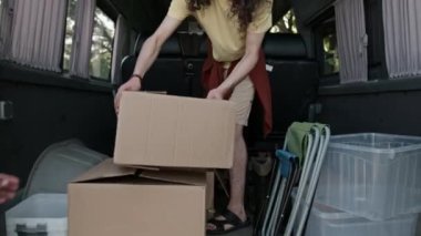 Yaz günü ormana yapılan çöp toplama gezisinde, sarı tişörtlü, kutularla çöp konteynırlarını birlikte taşıyan çeşitli çevreci aktivistlerin orta boy görüntüsü.