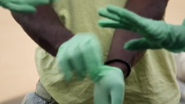 Tanınamayacak kadar çok ırklı erkek ve kadın çevreci gönüllülerin ellerinin yakın çekimi temizlik işi için lastik eldiven takması, takım ruhunu güçlendirmek ve üçe kadar saymak için el ele tutuşması.