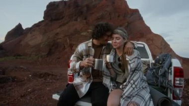 Orta boy beyaz bir çift kamyonet bagajında otururken kırmızı taşlı çölde dolaşırken, serin bir akşamda metal bardaklardan çay içerken, sarılıp, sohbet ederken.