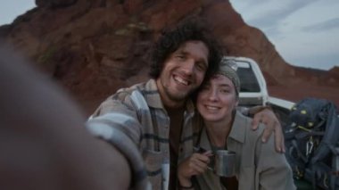 Kafkasyalı genç çiftin yan yana oturduğu orta boy bir fotoğraf. Mola sırasında pikapta kucaklaşıp çay içerken, akıllı telefondan selfie çekerken gülümserken, el sallarken, kameraya bakarken.