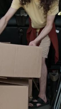 Minibüsten kutuları ve çöp konteynırlarını çıkarırken yaz günü park temizleme etkinliğine hazırlanan çoklu etnik çevre gönüllülerinden oluşan bir ekipten oluşan bir mercekle dikey yakınlaştırma çekimi.