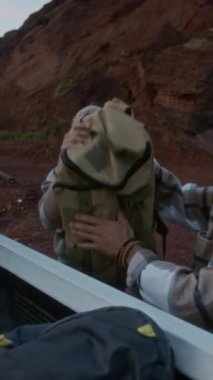 Kafkasyalı genç çiftin kamyondan sırt çantalarını alıp çölde, el ele tutuşup, gece boyu kamp yapmaya gittiklerinin tam dikey görüntüsü.