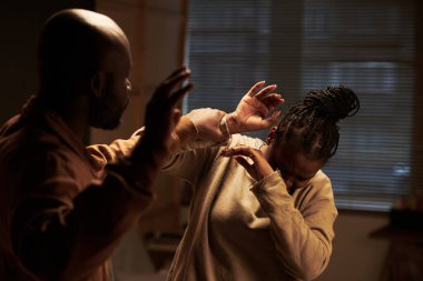 Savunmasız bir kadın, kavgada ya da tartışmada kafasını bileğinden tutup diğer eliyle ona vuran agresif bir erkekten kafasını saklıyor.