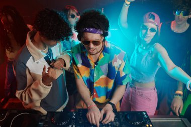 İki kültürlü erkeğin yüksek açılı bir görüntüsü. Biri sesleri karıştırırken diğeri de disko müziği yapıyor.