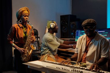 Müzisyenler kayıt stüdyosunda müzik besteliyor. Bir sanatçı saksafon çalarken, diğeri klavye ve sentezleyici sisteminde işbirliği yapıyor