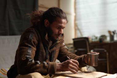 Sanat stüdyosunda resim çizmeye odaklanan Afrikalı Amerikalı bir adam sanatsal süreci ve yaratıcılığı yansıtan samimi bir anı resmediyor.