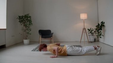 Sıradan giysiler içindeki genç sporcunun evde antrenman yaparken şınav çekerken tam pozu.