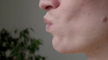 Side extreme closeup of guy doing face fitness and gymnastics for mouth, moving lips indoors