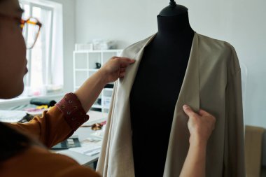 Genç bayan terzi ya da moda tasarımcısının yeni koleksiyon üzerinde çalışırken yeni gri ceket denemesi.