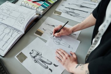 İş yerinde duran tanınmayan erkek modacının yüksek açılı elleri ve yeni moda koleksiyonu için çizimler.