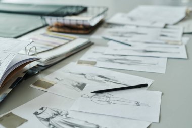 Yeni sezonluk koleksiyon hazırlıkları sırasında modern moda tasarımcısının çizdiği şık kıyafetlerin birinde yatan kalem.