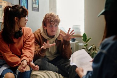 Bir grup genç yetişkin, günlük, yaratıcı bir çalışma ortamında bir film projesiyle ilgili animasyonlu bir tartışmaya girişirken, bir kişi kameraya bakar ve diğerleri başka yöne bakar.