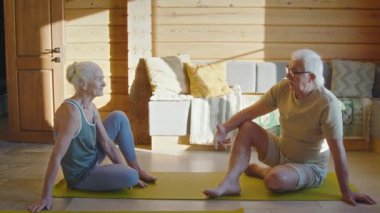 Spor kıyafetleri içinde yaşlı evli çiftlerin oturma odasında oturmuş, sohbet ediyor, sabah egzersizinden sonra yaşanan zorlukları ve sorunları tartışıyor.