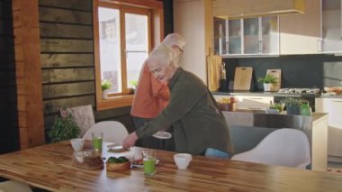 Sabahları sağlıklı bir kahvaltı için masa hazırlayan son sınıf Kafkas çifti. Sandviç, salata, meyve suyu ve kek getirirken aynı zamanda neşeyle sohbet ediyor, şakalaşıyor ve gülümsüyor.