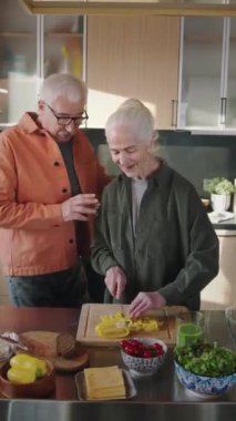 Orta boy, çapkın, neşeli, kıdemli, beyaz bir adamın karısını kucaklaması, mutfakta sebze kesmesi, sohbet etmesi, iltifat etmesi, her ikisi de gülümseyip gülmesi.