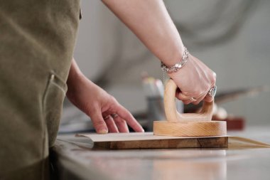 Yuvarlak ahşap baskı el yapımı eskiz ya da kağıt üzerinde desenleri olan tanınmayan genç bir zanaatkar kadının elleri