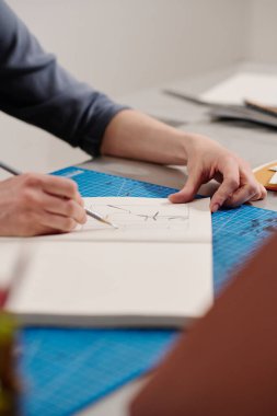 Kalem ve açık not defteriyle tanınmayan genç kadın sanat tasarımcısının elleri baskı için yeni çizimler çiziyor.