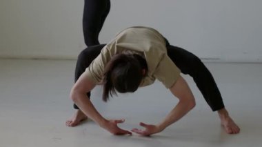 Kaslı erkek dansçı Plie squat 'ta gövde daireleri çiziyor. Stüdyoda provadan önce ısınma sırasında arka planda egzersiz yapan kadın partner.