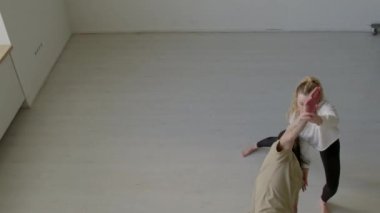 Çağdaş tarzda dans eden ve stüdyoda prova yaparken eş kaldırma egzersizleri yapan genç artistik çiftin yüksek açı çekimi.