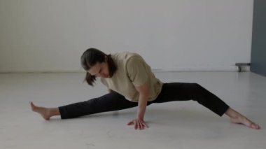 Profesyonel erkek dansçı, stüdyoda provadan önce hareketli bir ısınma yaşarken yan yana geriliyor ve hamle yapıyor.