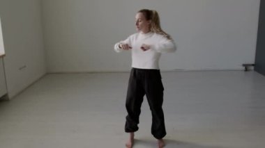 Prova öncesi dinamik ısınma sırasında stüdyoda duran ve gövde dönüşleri yapan genç bayan dansçılarla dolu bir çekim.