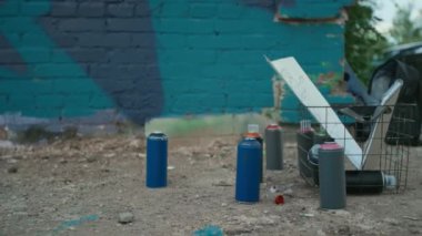 Kapalı çekim hiç kimse grafiti sprey boya ile şişeleri çeşitli renkler, kağıt çizimler ve tasarımlar ile tel sepet, arka sokakta mavi tuğla duvar yanında yaz günü
