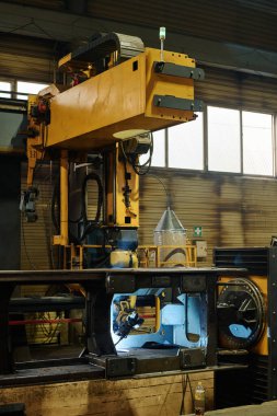 Heavy machinery operating inside an industrial facility constructed of metal and glass materials. No workers visible in the surroundings clipart