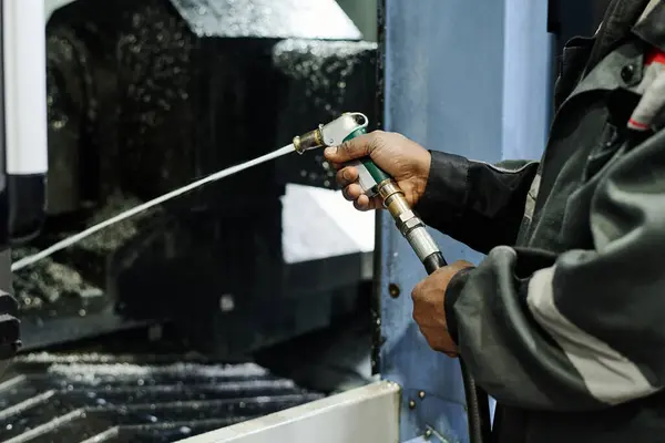 stock image Person operating machinery by holding and maneuvering a tool in an industrial environment where various equipment and heavy-duty machines are visible and being used