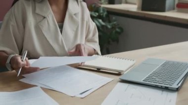 İspanyol bayan öğretmenin derslerden sonra tek başına çalıştığı, öğrencilerin test kağıtlarını düzelttiği ve işaretlediği orta boy yakın çekim.