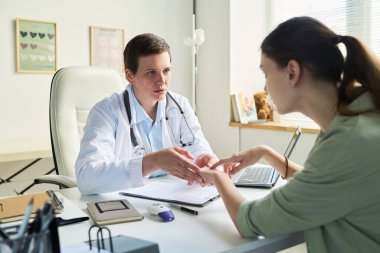 Klinikteki hastaya profesyonel tıbbi danışmanlık, hastanın elini tutmak ve endişe göstermek.