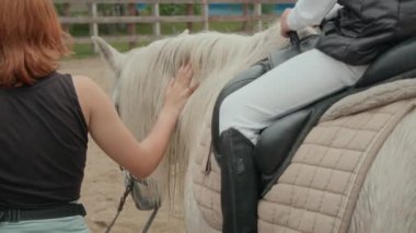 Genç, kızıl saçlı, beyaz bir kadının, ata binme tekniği hakkında açıklama yaparken, jodhpur botlar ve pantolonlar giyen, tanınmayan bir biniciyle birlikte at etrafında yürüdüğünü gördüm.