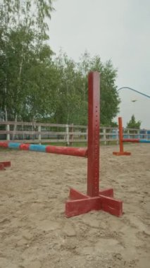Genç bayan jokeyin atletizm atının sırtında oturduğu dikey çekim ve gösteri atlama yarışmasına hazırlanan engelli atlayışlar.