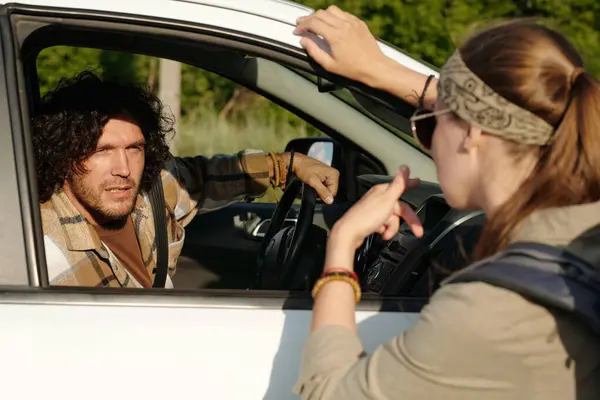 Stock image Young curly man in pickup truck looking at active female traveler asking him way or possibility to ride by his vehicle