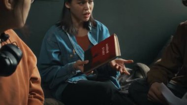 Modern yatak odasında toplanan korku kitabına dayalı film konusunu tartışan üç farklı sinematografi öğrencisinin fotoğrafını çıkar.