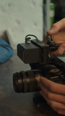Kiralama atölyesindeki müşteriye profesyonel video kamerayı kullanmanın bir yolunu tarif eden isimsiz işçinin elleri dikey olarak yakın çekim