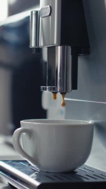 Dikey olarak hiç kimse beyaz bardağı kahve ya da kapuçino yapmak için espresso ile dolduran ev yapımı kahve makinesine yakın çekim yapmaz ve iş günü ya da evde kahve içen tanınmamış bir adamın eli onu almaz.
