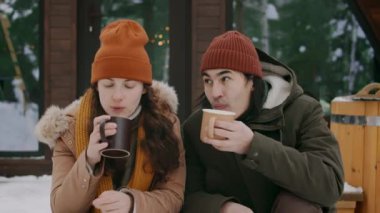 Orta halli, genç Asyalı koca ve Kafkas karısının kış günü Eko Otel 'in verandasında dinlenirken sıcak kahvenin tadını çıkarırken, sohbet ederken, sarılırken ve öpüşürken.