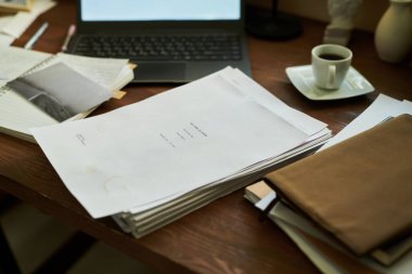 Düzenli düzenlenmiş masaüstü sergilenen kağıtlar, açık bir dizüstü bilgisayar, defter ve buharı tüten kahve verimli bir çalışma ortamı yaratıyor. Çalışmak ya da uzak çalışma için ideal kurulum