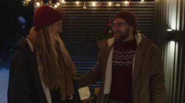 Orta yaşlı bir çiftin ışıklarla dekore edilmiş terasa çıkıp Noel 'de kırsalda birlikte vakit geçirip, sarılıp eğlendiği orta yaşlı bir fotoğraf.